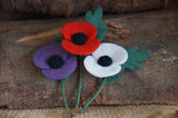 Purple, Red and White needle felted poppies grouped together on a rustic wooden log