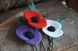 close up view of 3 needle felted poppies on a wooden log for armistice day